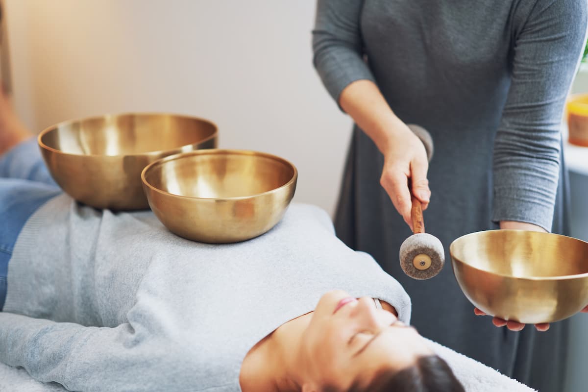 Woman receiving sound healing with Himalayan singing bowls