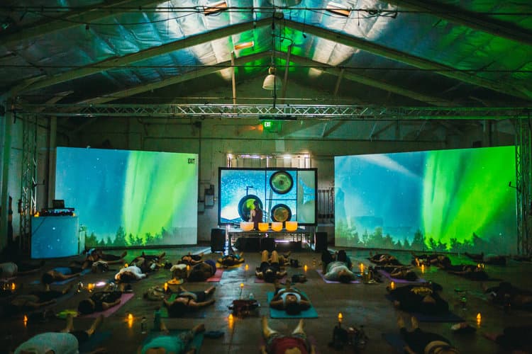 Jamie Bechtold playing a gong and crystal singing bowl sound bath in large venue