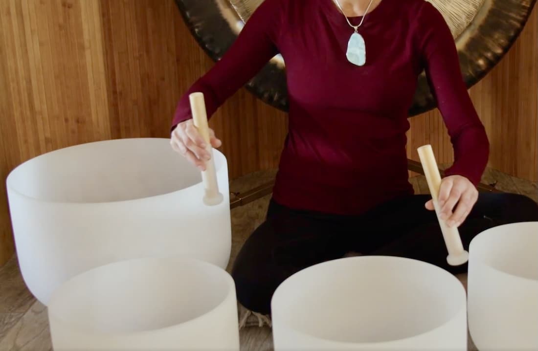 Jamie Bechtold playing crystal bowls in a sound bath using both hands