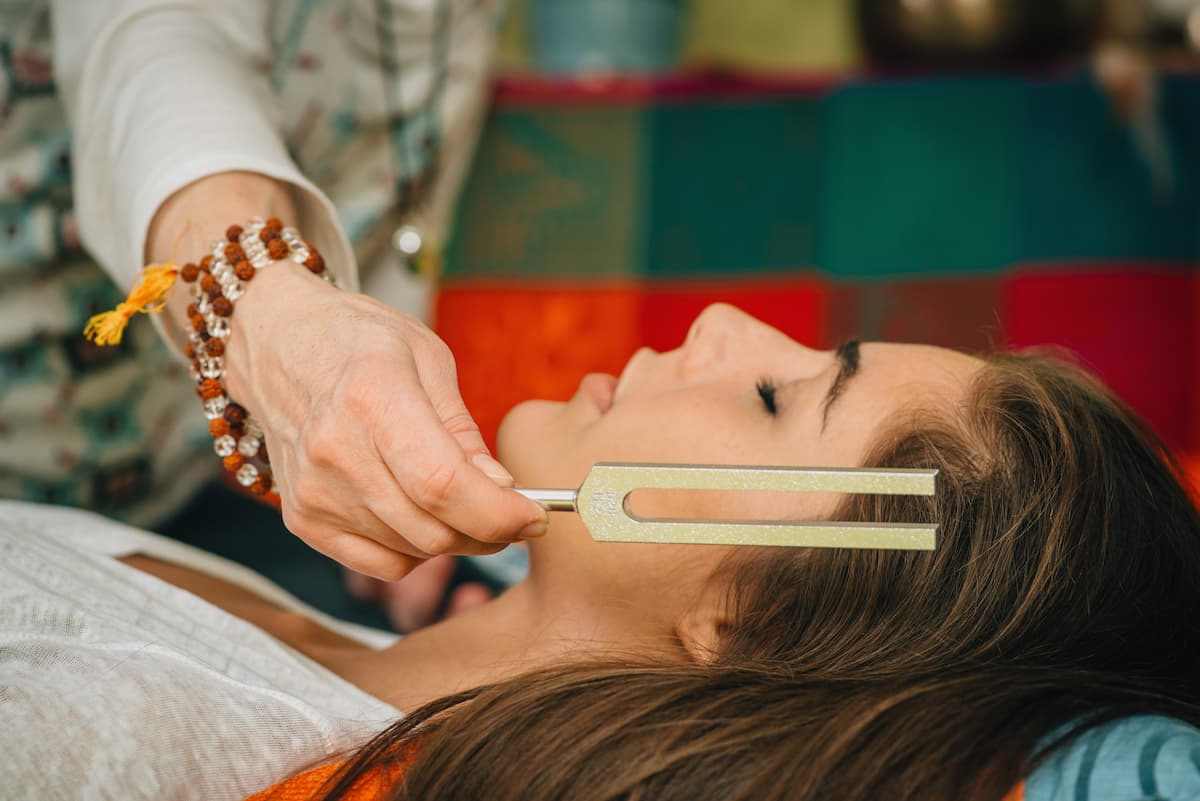 Woman receiving sound therapy session with tuning fork