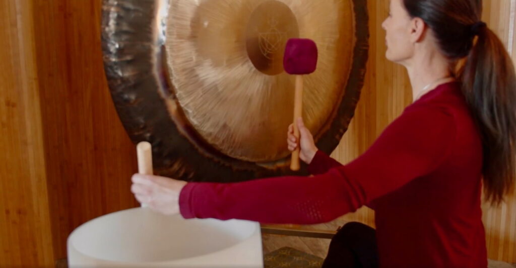 Jamie Bechtold playing a gong and crystal singing bowl